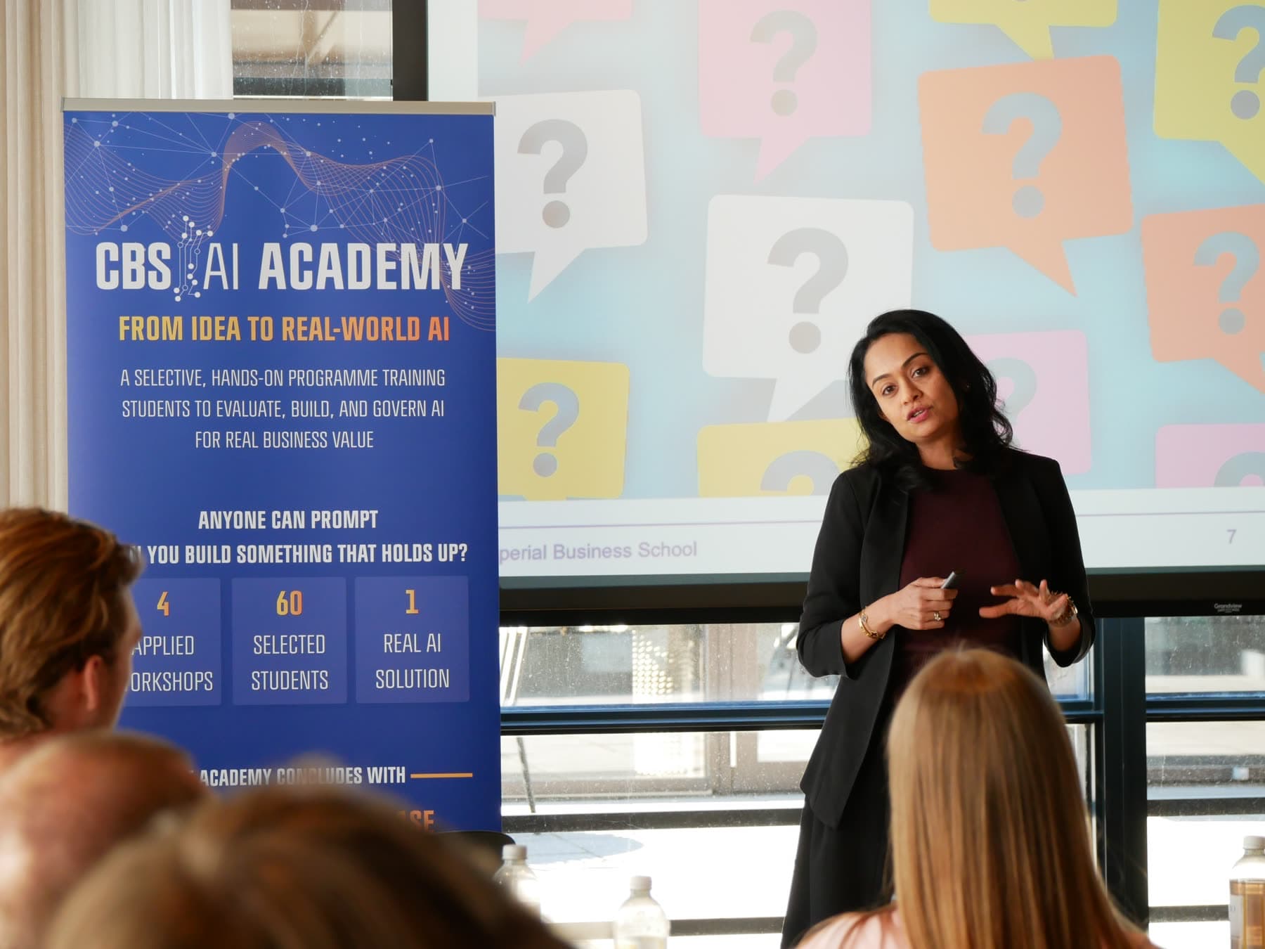 A speaker addressing the room beside a CBS AI Academy banner